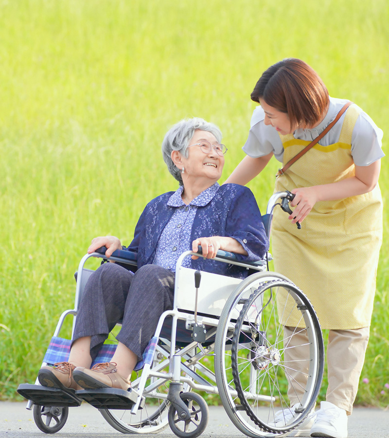 車椅子をおすスタッフと笑顔の女性
